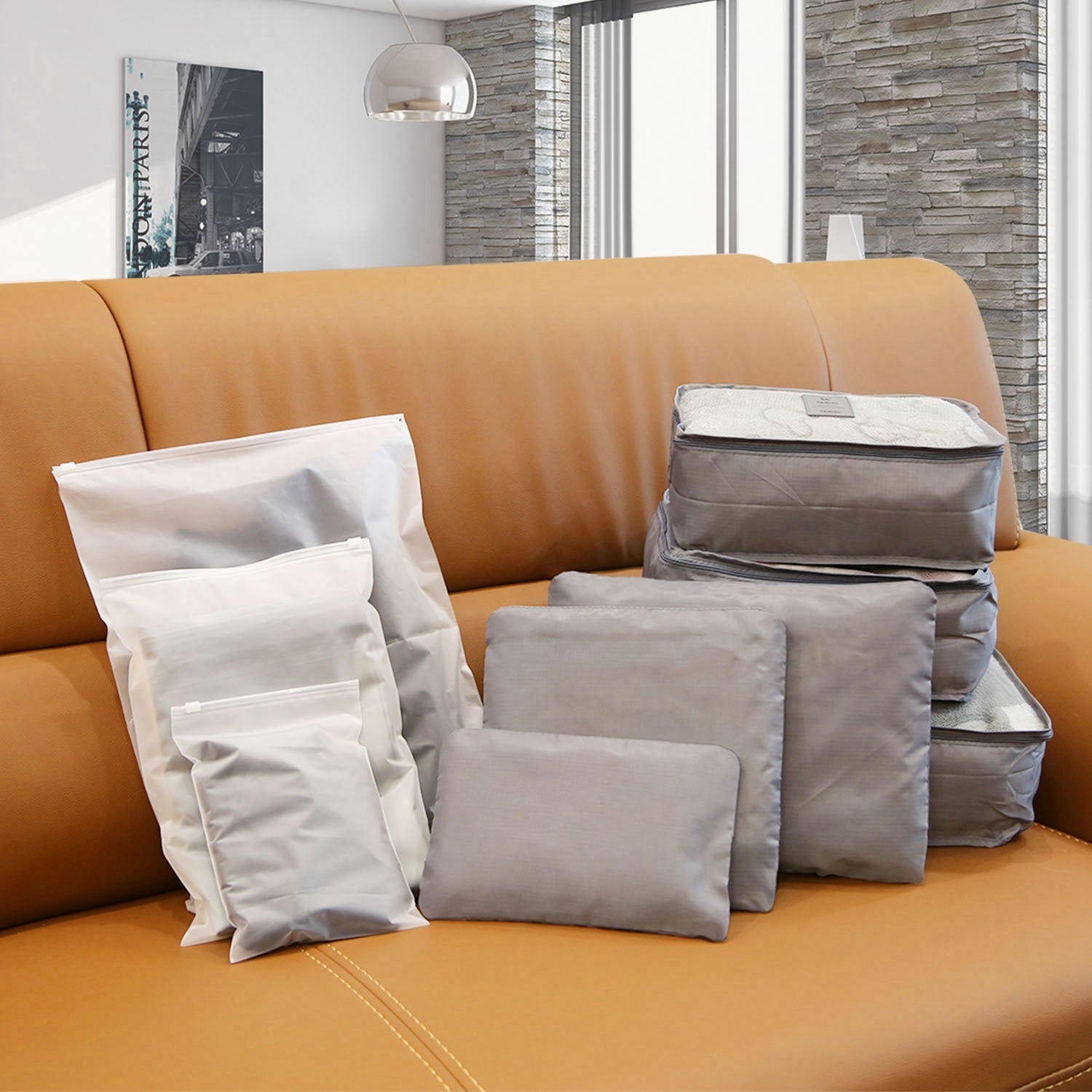 Set of four 9Pcs Clothes Storage Bags Water-Resistant Travel Luggage Organizer Clothing Packing Cubes of varying sizes with clothing items, displayed next to a folded floral blouse, all on a white background.