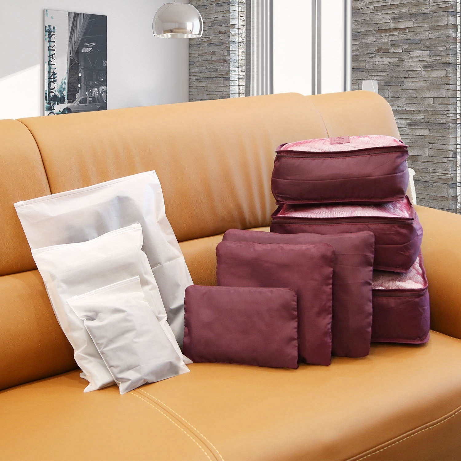 Set of four 9Pcs Clothes Storage Bags Water-Resistant Travel Luggage Organizer Clothing Packing Cubes of varying sizes with clothing items, displayed next to a folded floral blouse, all on a white background.