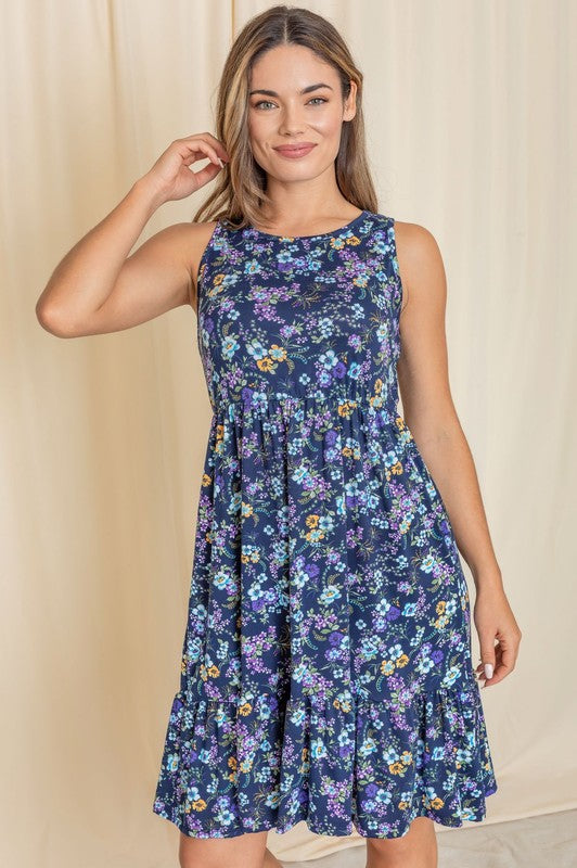 A person wearing the Sleeveless Botanical Floral Tiered Dress poses gracefully in front of a pink curtain.