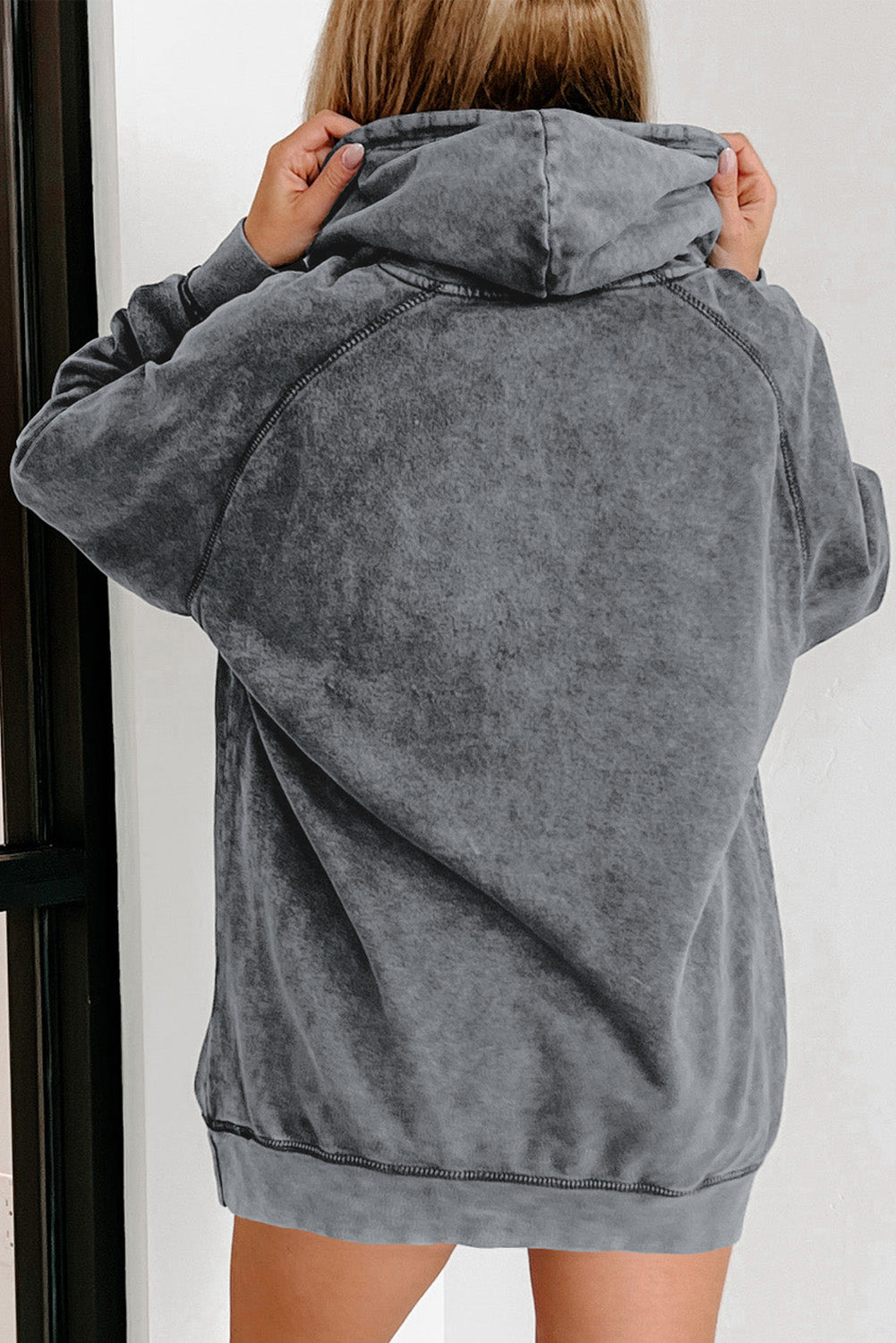 A person with blonde hair is standing with their back to the camera, wearing a Gray Mineral Wash Kangaroo Pocket Drawstring Pullover Hoodie.