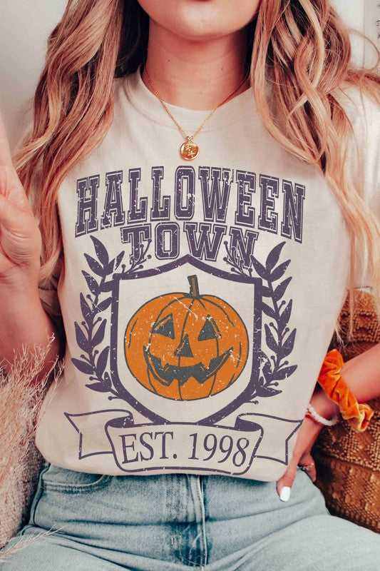 A person wearing a premium cotton HALLOWEEN TOWN Graphic Tee featuring an est. 1998 jack-o'-lantern design, displaying a peace sign with their right hand.