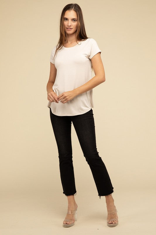 A person with long hair is wearing a blue Flowy Round Hem Rayon Short Sleeve Top and black pants, standing against a plain beige background.