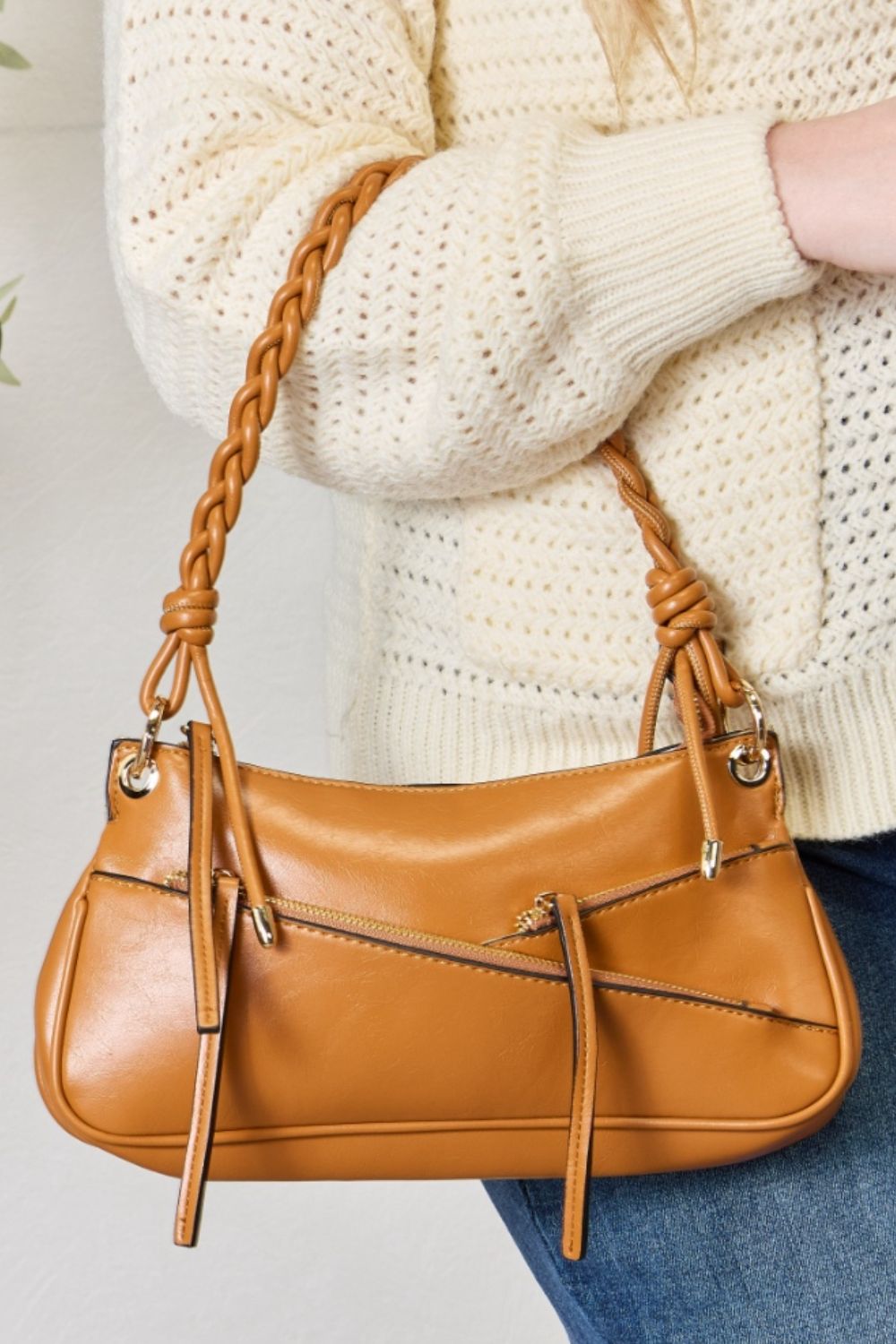 A person exudes bohemian elegance, carrying the SHOMICO Braided Strap Shoulder Bag, expertly crafted with advanced leather techniques and braided handles, while wearing a cream sweater and blue jeans.