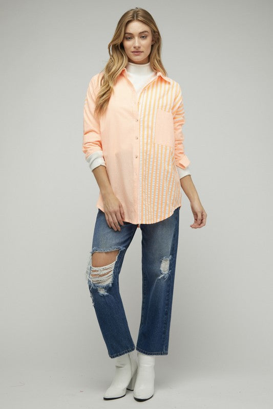 A person wearing a light pink Stripe Button Down Long Sleeve Shirt with rolled-up sleeves and jeans stands with their hands behind their head against a plain background.