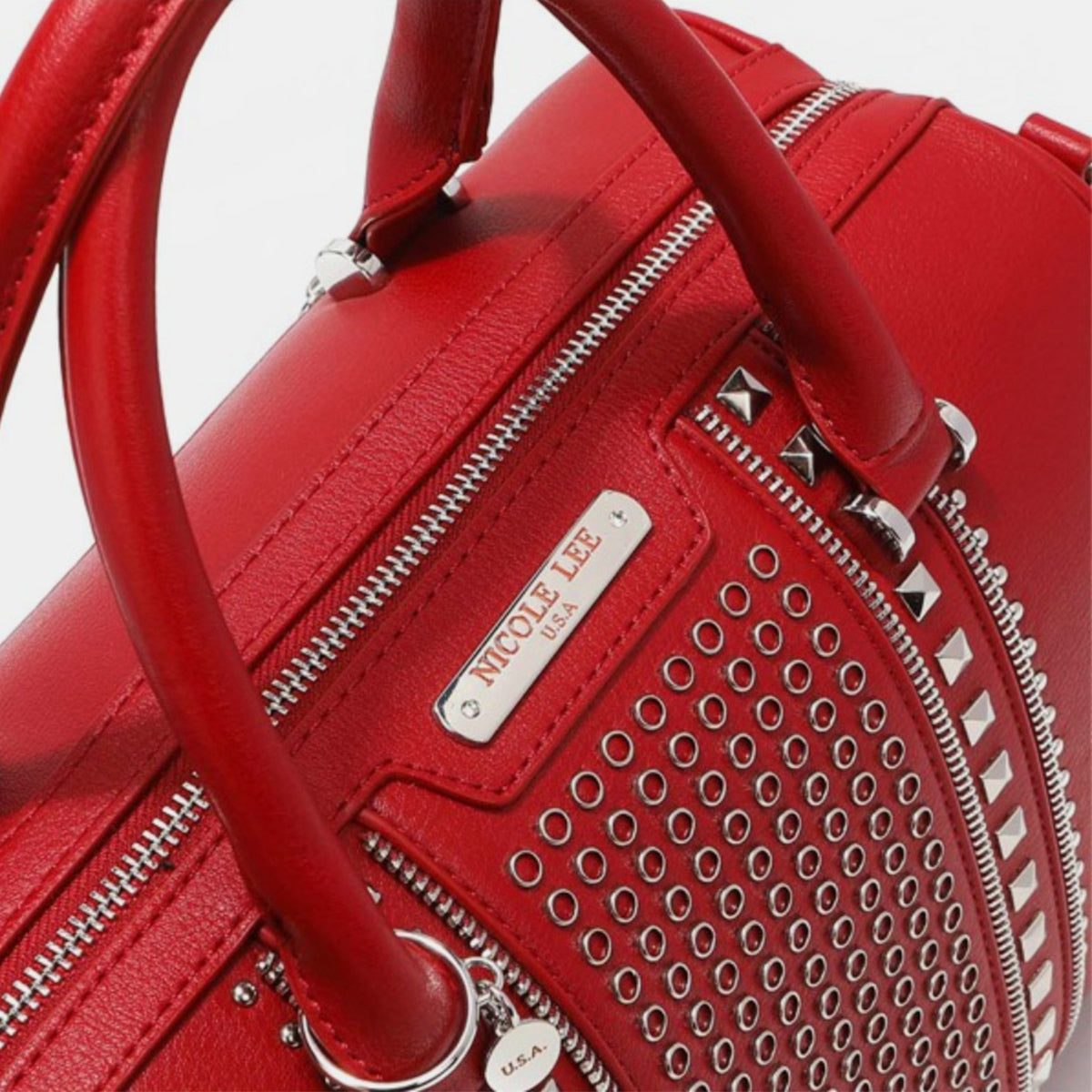 Nicole Lee USA Studded Boston Bag, crafted from luxurious vegan leather in red, showcases a design with two handles and metallic stud and ring embellishments on the front.