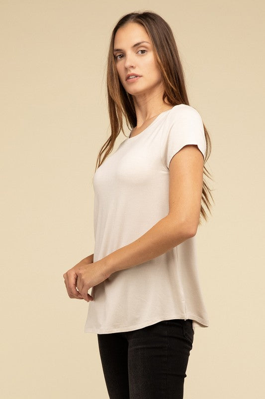 A person with long hair is wearing a blue Flowy Round Hem Rayon Short Sleeve Top and black pants, standing against a plain beige background.