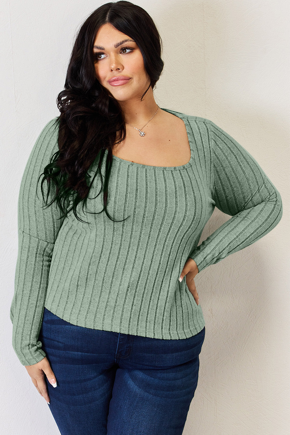 A person is standing and smiling, wearing the Basic Bae Full Size Ribbed Long Sleeve T-Shirt in light brown along with jeans. The basic style is perfect for any casual outing.