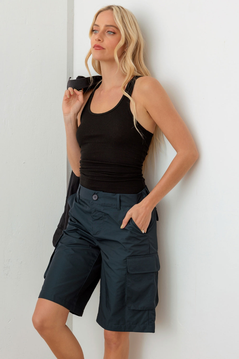 Person wearing a black sleeveless top and Le Lis Navy Cargo Bermuda Shorts with pockets, perfect for a warm-weather wardrobe.