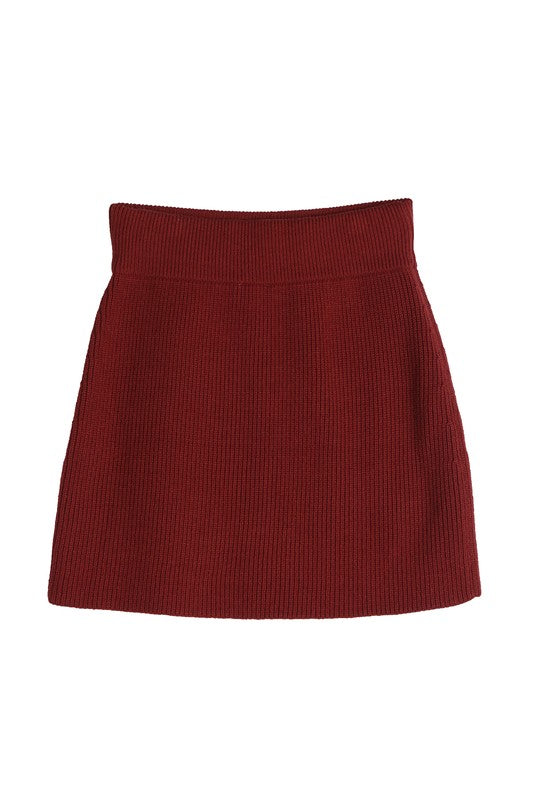 A person is showcasing the Ribbed knit crop top and skirt set in a vibrant red hue, standing out beautifully against a beige background.