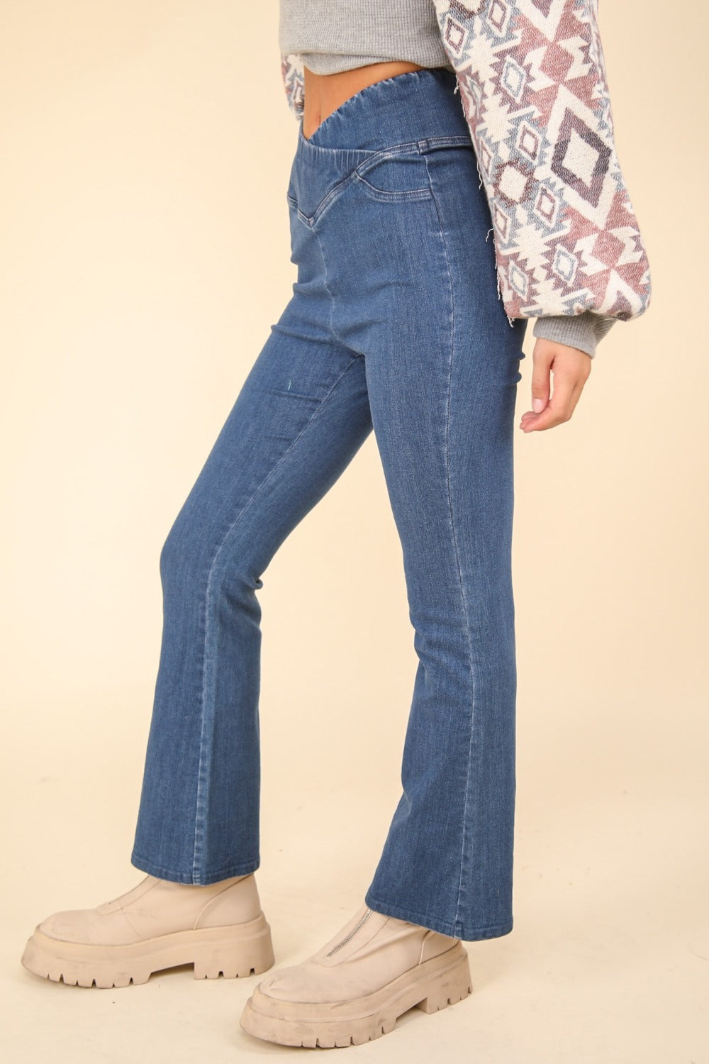 Person wearing VERY J Washed Denim Stretchy Crossover Waist Leggings with a hint of flared leg, and beige ankle-length boots. Only the lower half of the body is visible.