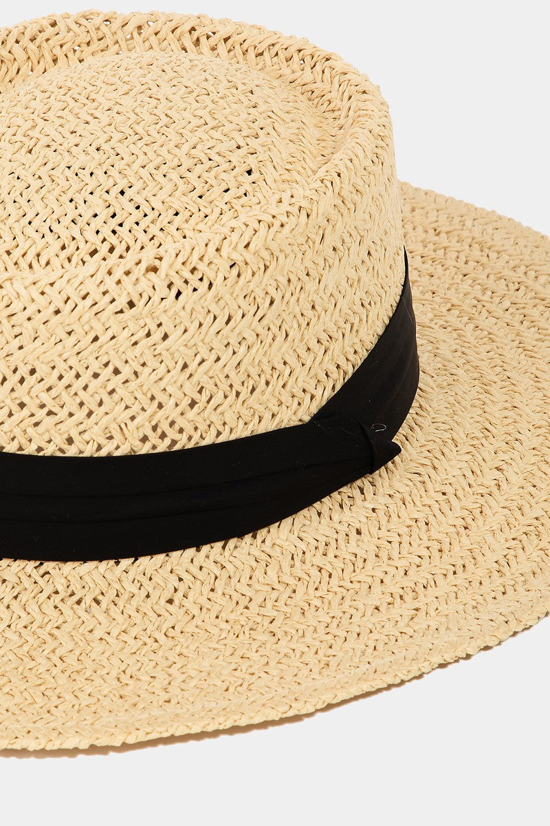 The Fame Straw Braided Pork Pie Hat features a wide brim and a black band around the base, making it the perfect versatile accessory to add summer charm to any outfit.