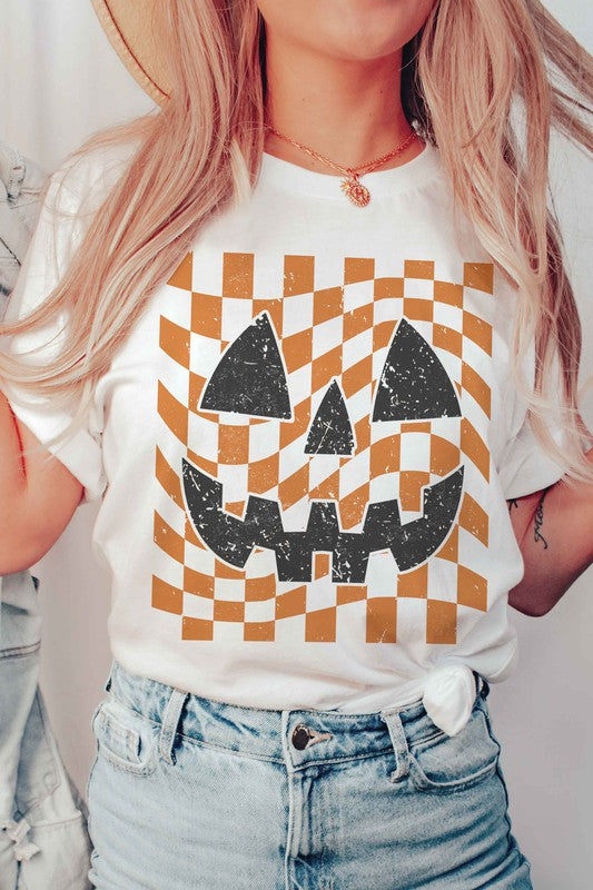 Person wearing a CHECKER PUMPKIN FACE Graphic Tee, made from 100% cotton, paired with high-waisted blue jeans.