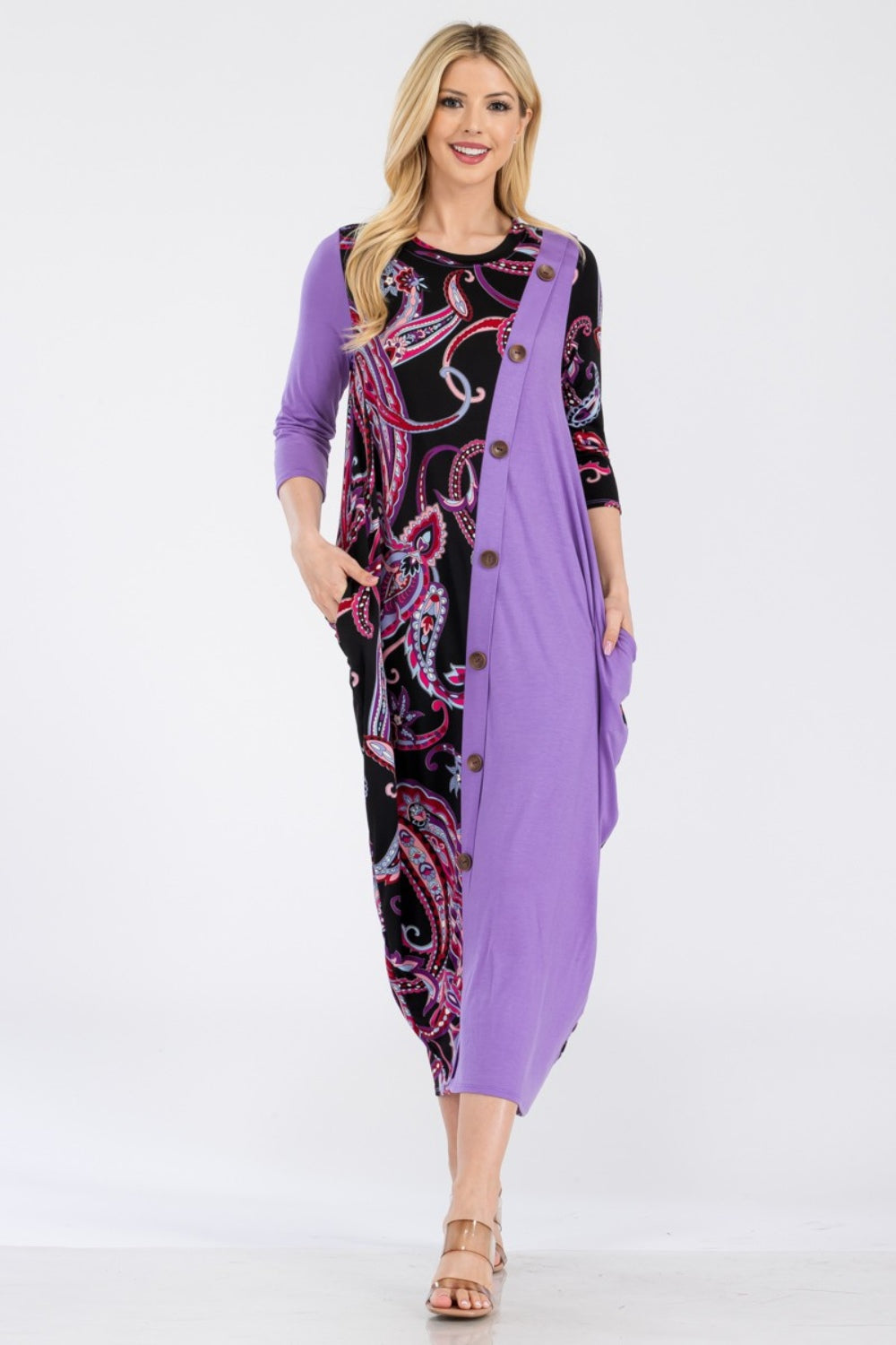 A woman wearing the Celeste Full Size Paisley Contrast Midi Dress with pockets, showcasing a versatile purple and black paisley print, button front detail, and long sleeves.