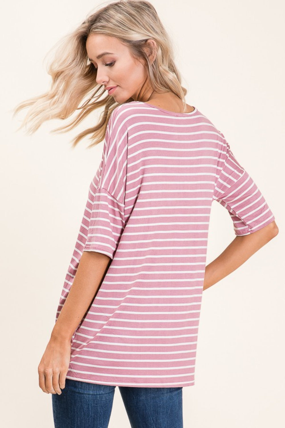 A person wearing a BOMBOM Striped Round Neck Half Sleeve T-Shirt in pink and white paired with blue jeans stands against a neutral background.