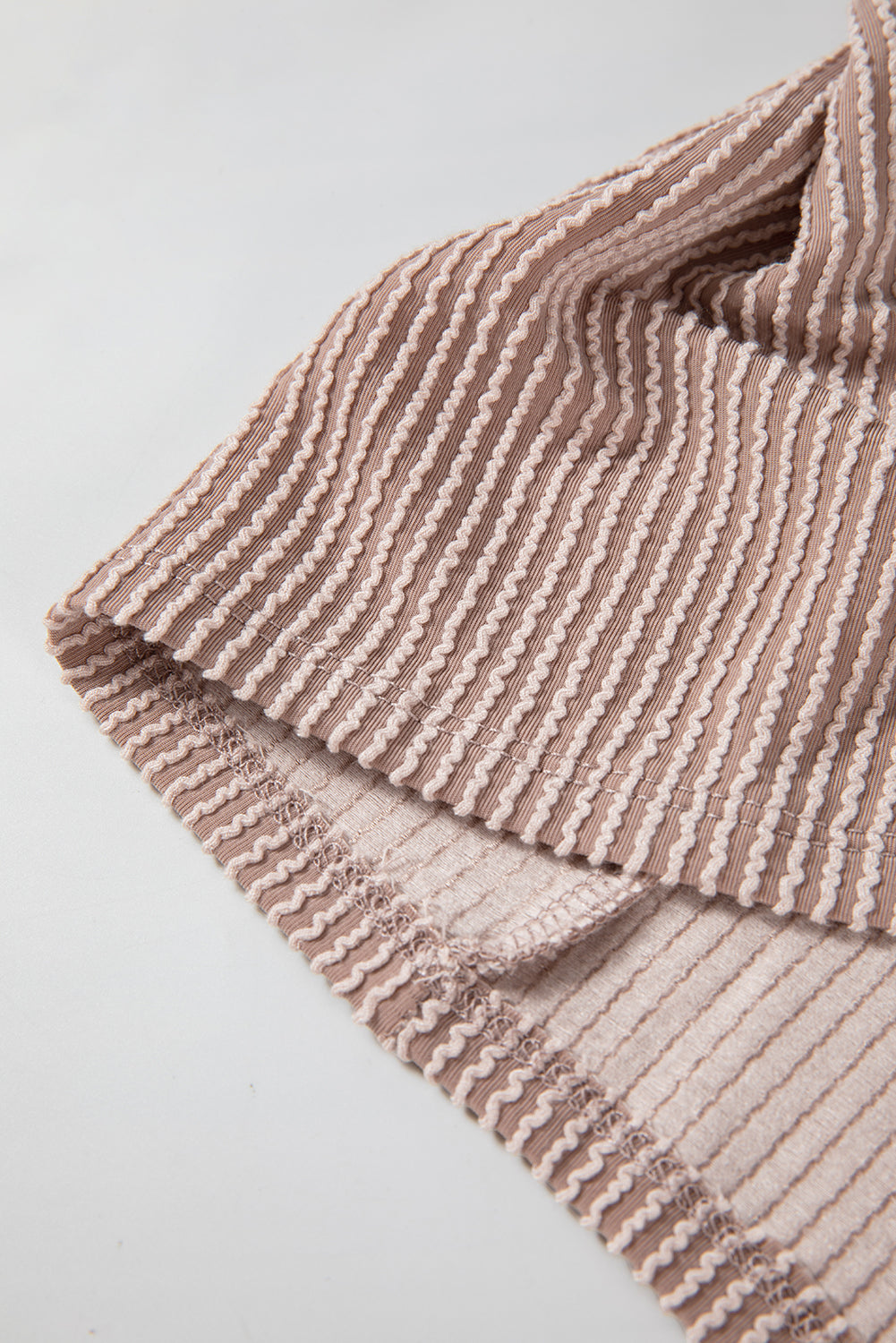 A person with long, wavy hair is facing away from the camera. They are wearing a Dark Brown Flap Pocket Patchwork Corded Drawstring Hoodie and blue jeans, holding a brown shoulder bag.