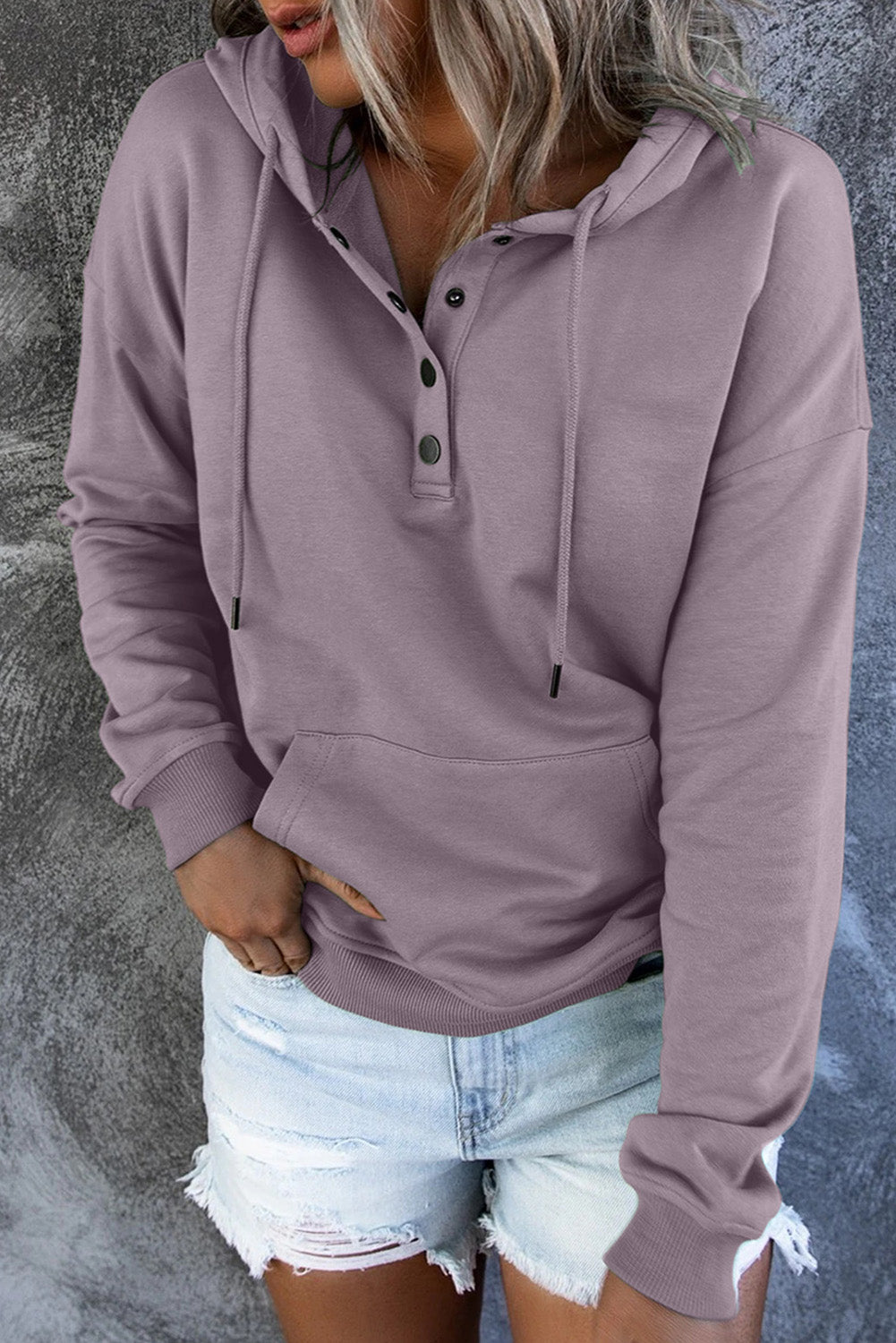 Back view of a person wearing a Purple Snap Button Pullover Hoodie with Pocket and light blue denim shorts with frayed hems, perfect for casual occasions, standing against a grey textured background.