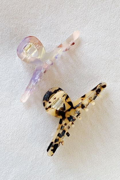 Two different colored Barely There Hair Claws placed on a light-colored surface.