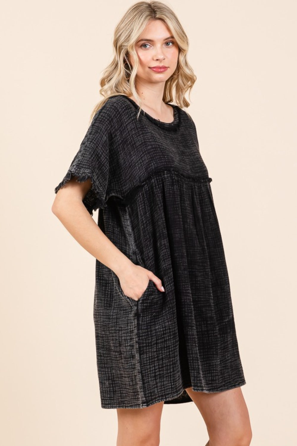 A person is wearing the Culture Code Full Size Short Sleeve Babydoll Texture Dress with Pockets, in black, standing against a plain background.