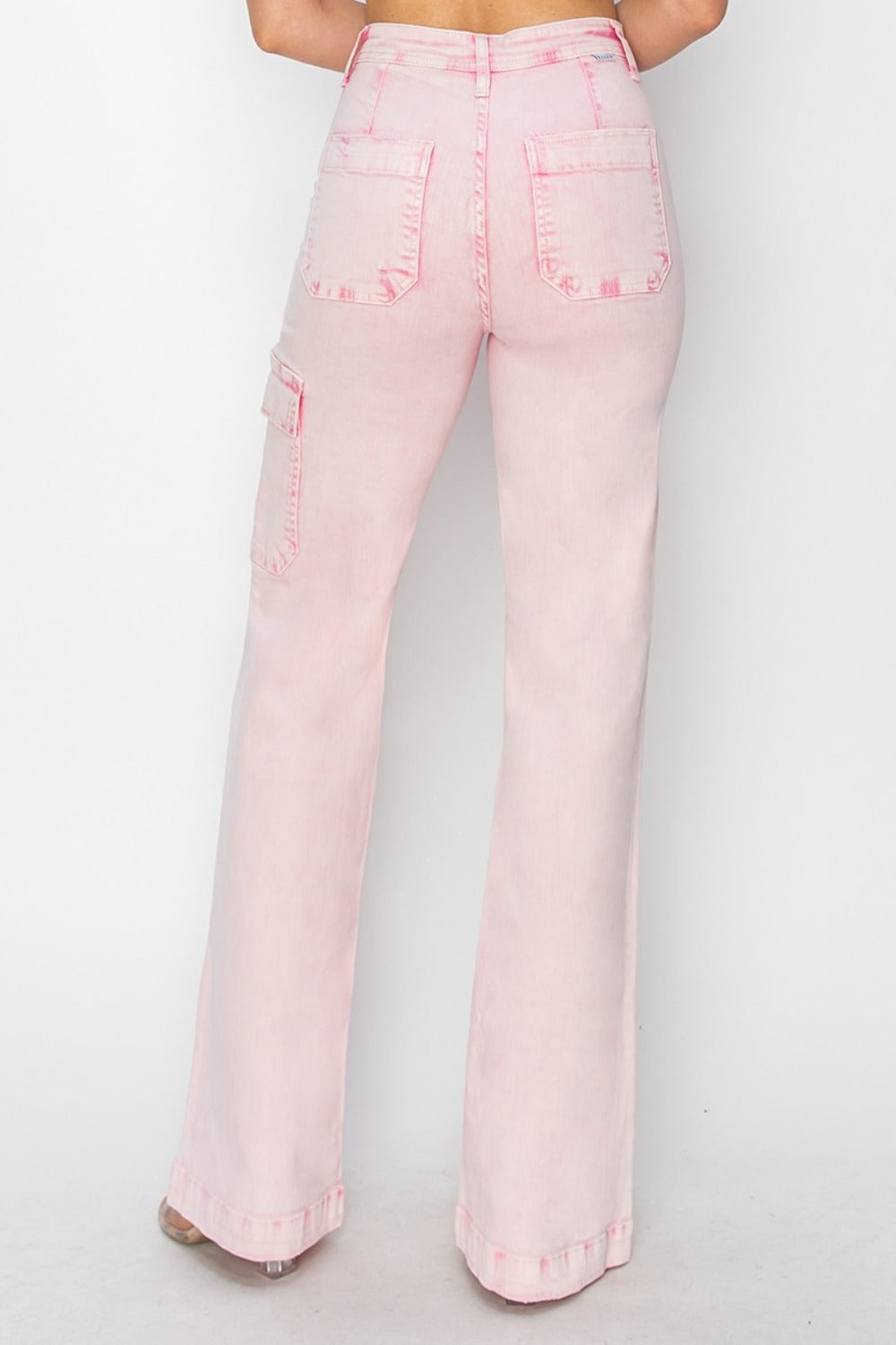 Person wearing the RISEN Full Size High Rise Wide Leg Cargo Pocket Jeans in light pink, featuring front pockets and a button-zip closure, standing against a white background.