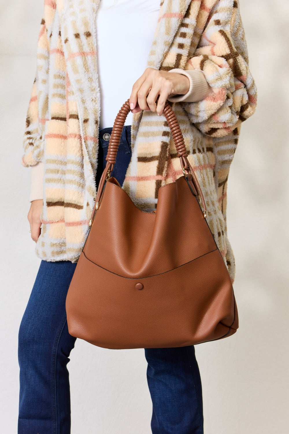 Person carrying a SHOMICO Vegan Leather Handbag with a front pocket and coiled handles, showcasing both versatility and durability.