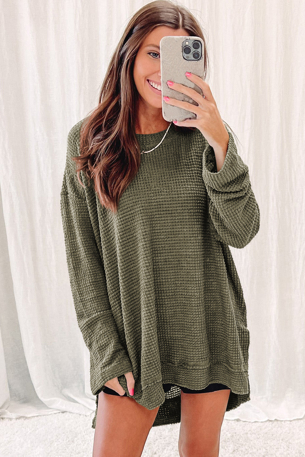 Person wearing a trendy Green Waffle Knit Drop Sleeve High Slits Oversized Top takes a mirror selfie, showcasing the cozy waffle knit texture along with their upper and part of their lower body.