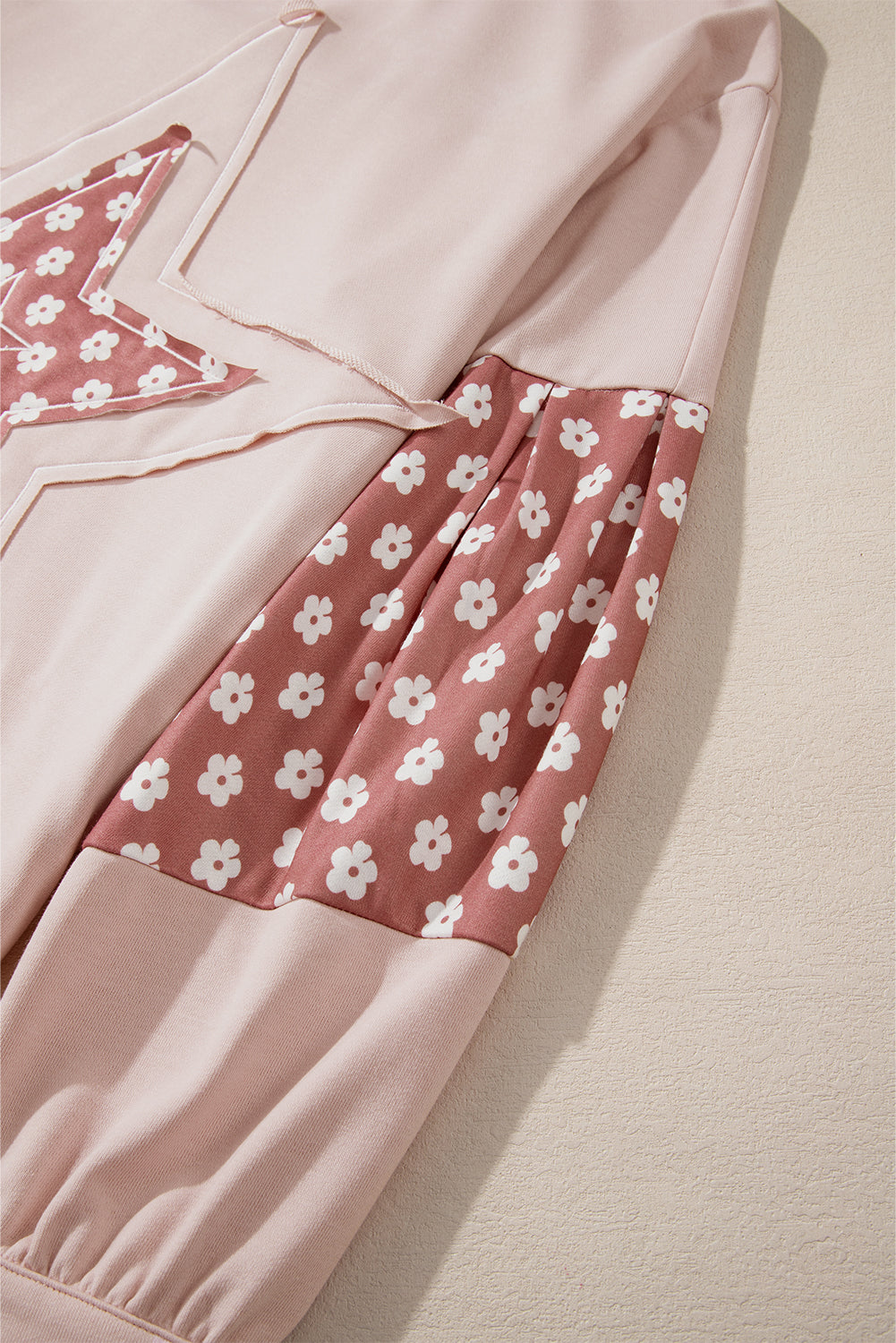 Person wearing the Delicacy Floral Patchwork Star Pattern Drawstring Hoodie, showcasing the floral patchwork design on the hood and sleeves from the back.