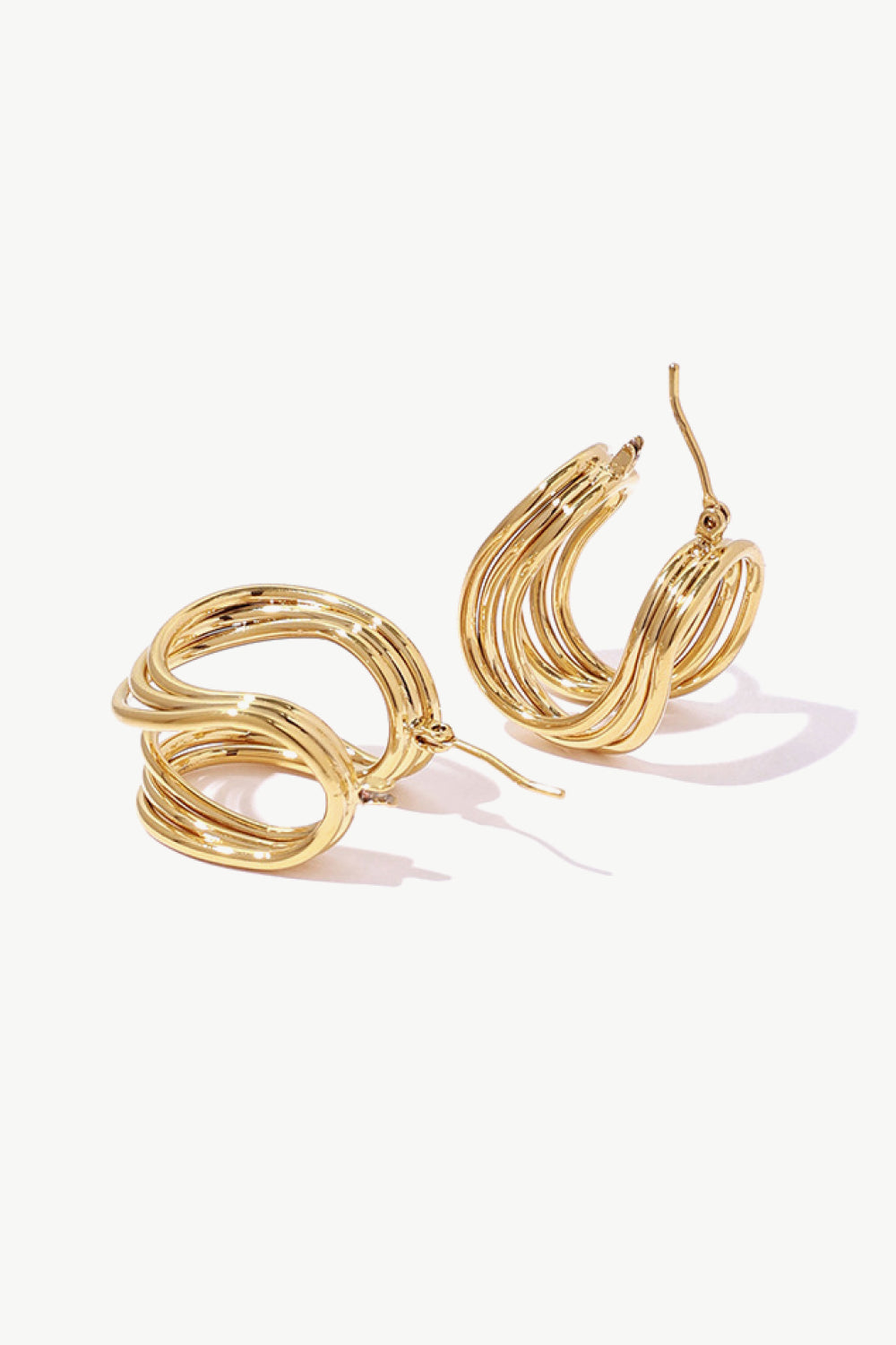 The U-Shaped Hoop Earrings feature a layered, wavy design on a light background, making them a stunning addition to any jewelry collection. These exquisite brass earrings showcase elegant craftsmanship, perfect for both casual and formal occasions.