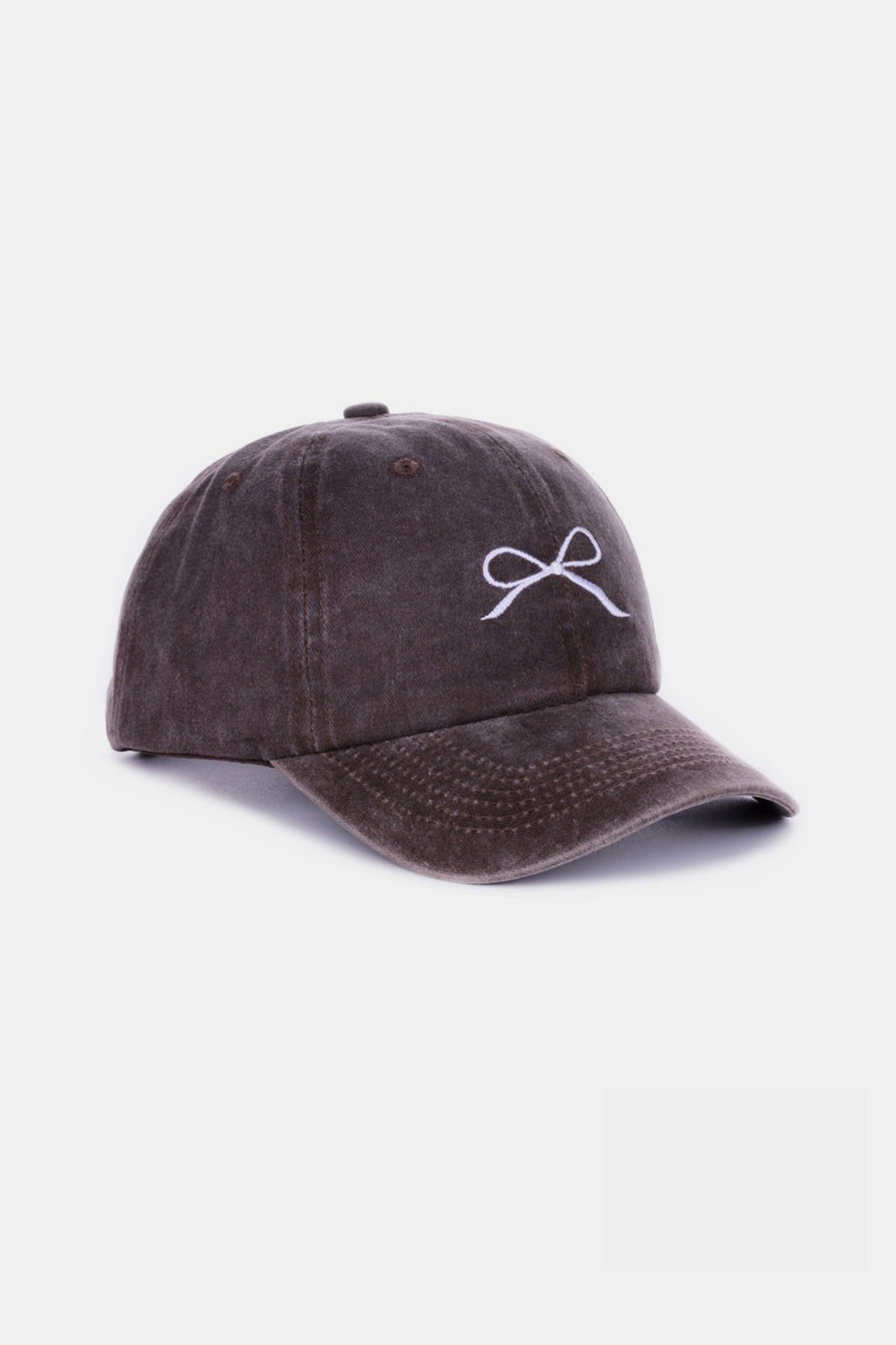 The Zenana Bow Embroidered Washed Cotton Cap features a pink design with a stylish white bow on the front, set against a plain, light background. This chic accessory seamlessly combines elegance and sportiness.