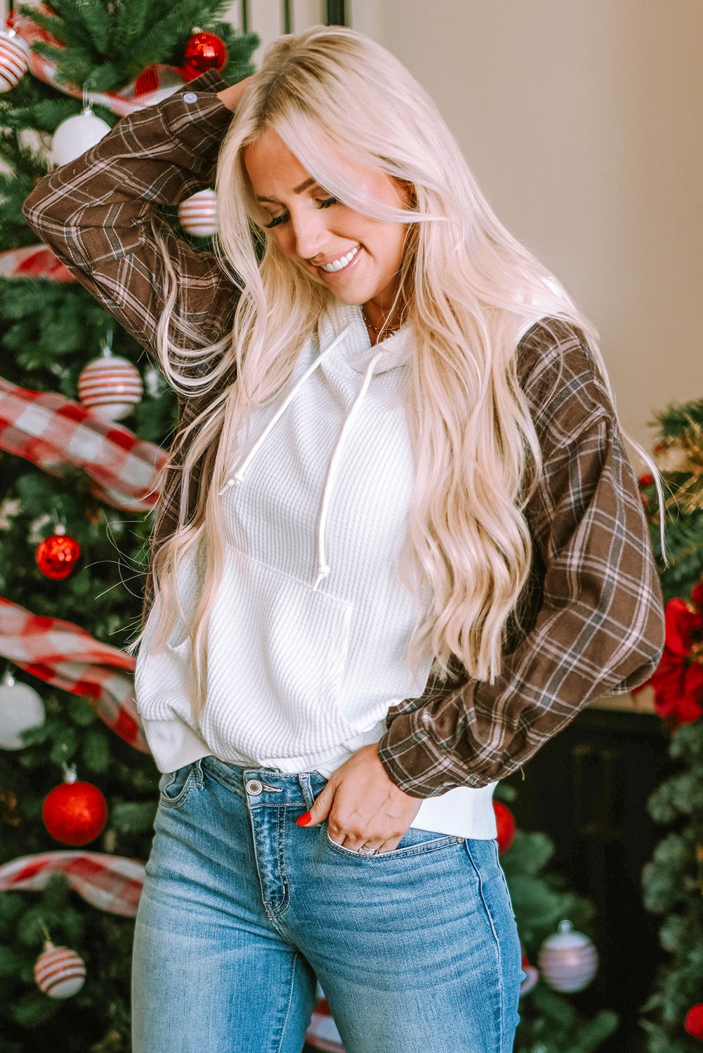 A person with blonde hair, wearing a White Waffle Patch Plaid Sleeve Kangaroo Pocket Hoodie, stands facing away in front of a decorated Christmas tree.