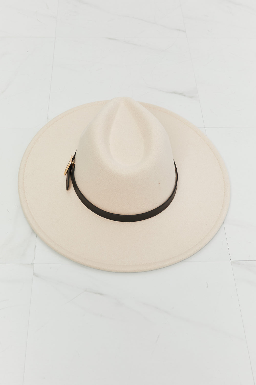 A woman with shoulder-length hair, wearing a Fame Ride Along Fedora Hat in beige with a black band, is seen from behind against a white background.