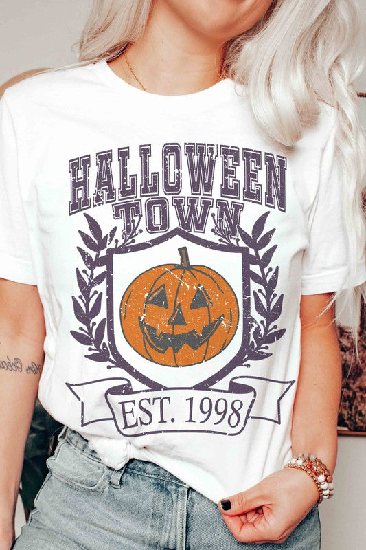 A person wearing a premium cotton HALLOWEEN TOWN Graphic Tee featuring an est. 1998 jack-o'-lantern design, displaying a peace sign with their right hand.