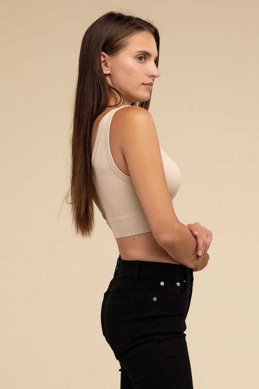 A person with long brown hair wearing the Ribbed Seamless Crop Top in light blue and black pants stands against a beige background, showcasing a perfect summer essential.