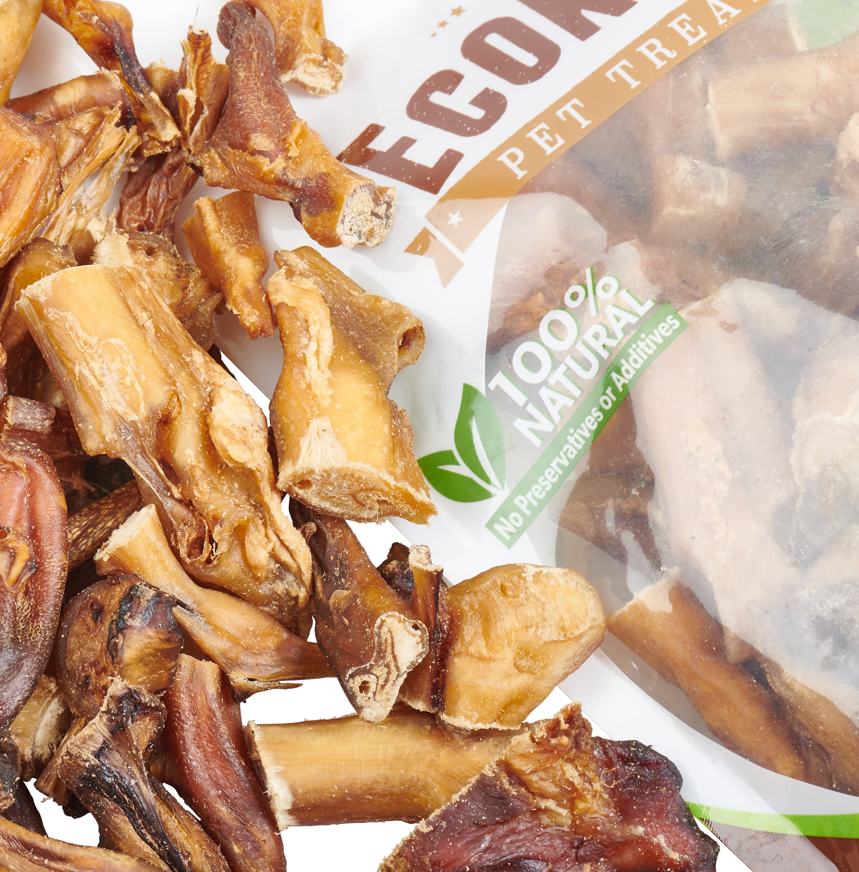 A bag of Grass-Fed Beef Bully Stick Bites by EcoKind, made from natural ingredients without any preservatives or additives, prominently displays its 100% natural claim. Various treats are attractively arranged in front of the packaging.