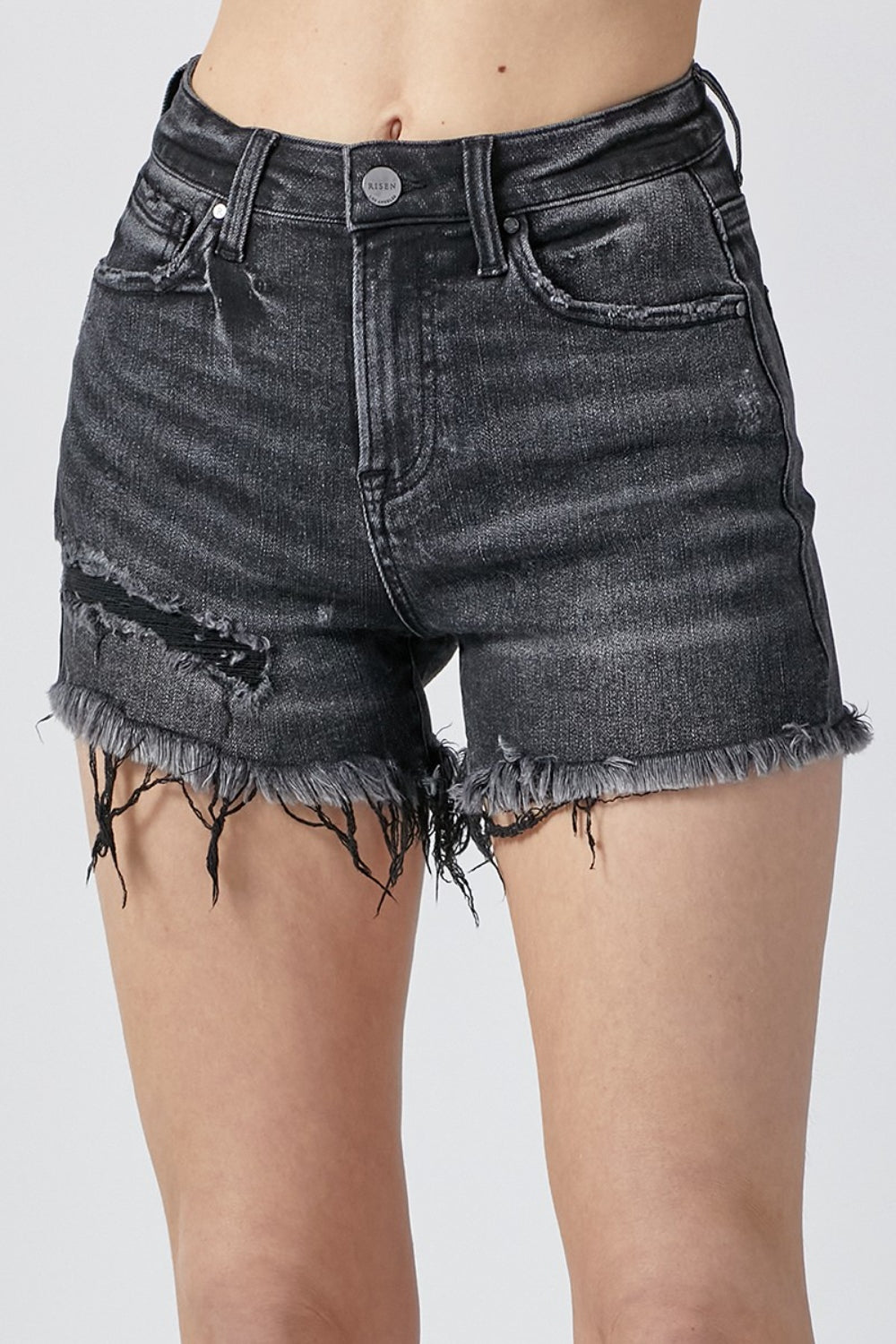 A person wearing RISEN Raw Hem Denim Shorts with Pockets, featuring high-waisted, distressed black design and a button and zipper closure, perfect for summer outfits.