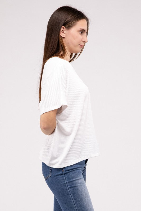 Woman wearing an oversized, short-sleeve Ribbed Striped Top in green and blue jeans, standing with her hands in her pockets against a plain background.