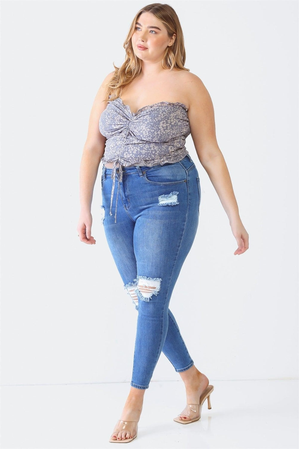 A person with long hair is wearing the Zenobia Plus Size Drawstring Smocked Floral Tube Top paired with ripped jeans, standing against a plain background—a perfect addition to any summer wardrobe.