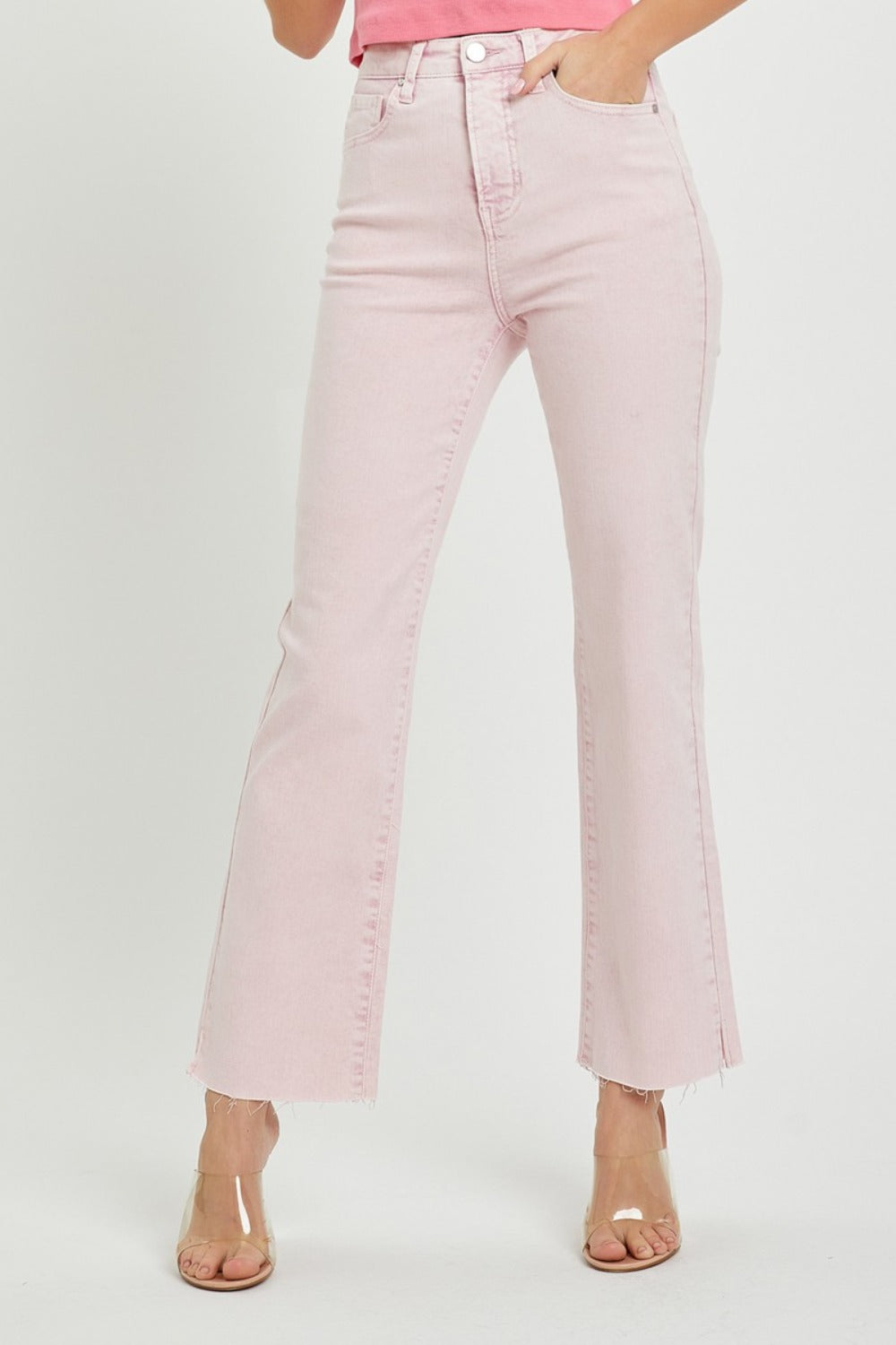 Person wearing RISEN Full Size High Rise Tummy Control Straight Jeans in light pink with a raw hem and clear heeled shoes against a plain white background.