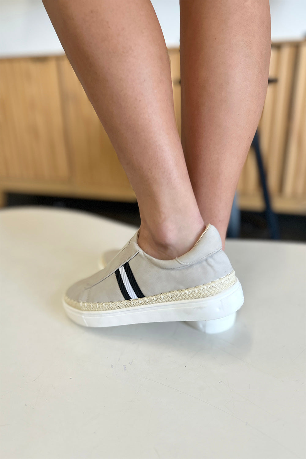 A person wearing the chic CCOCCI Striped Round Neck Sneakers in beige, featuring black and white stripes on a light surface, ideal for everyday wear.