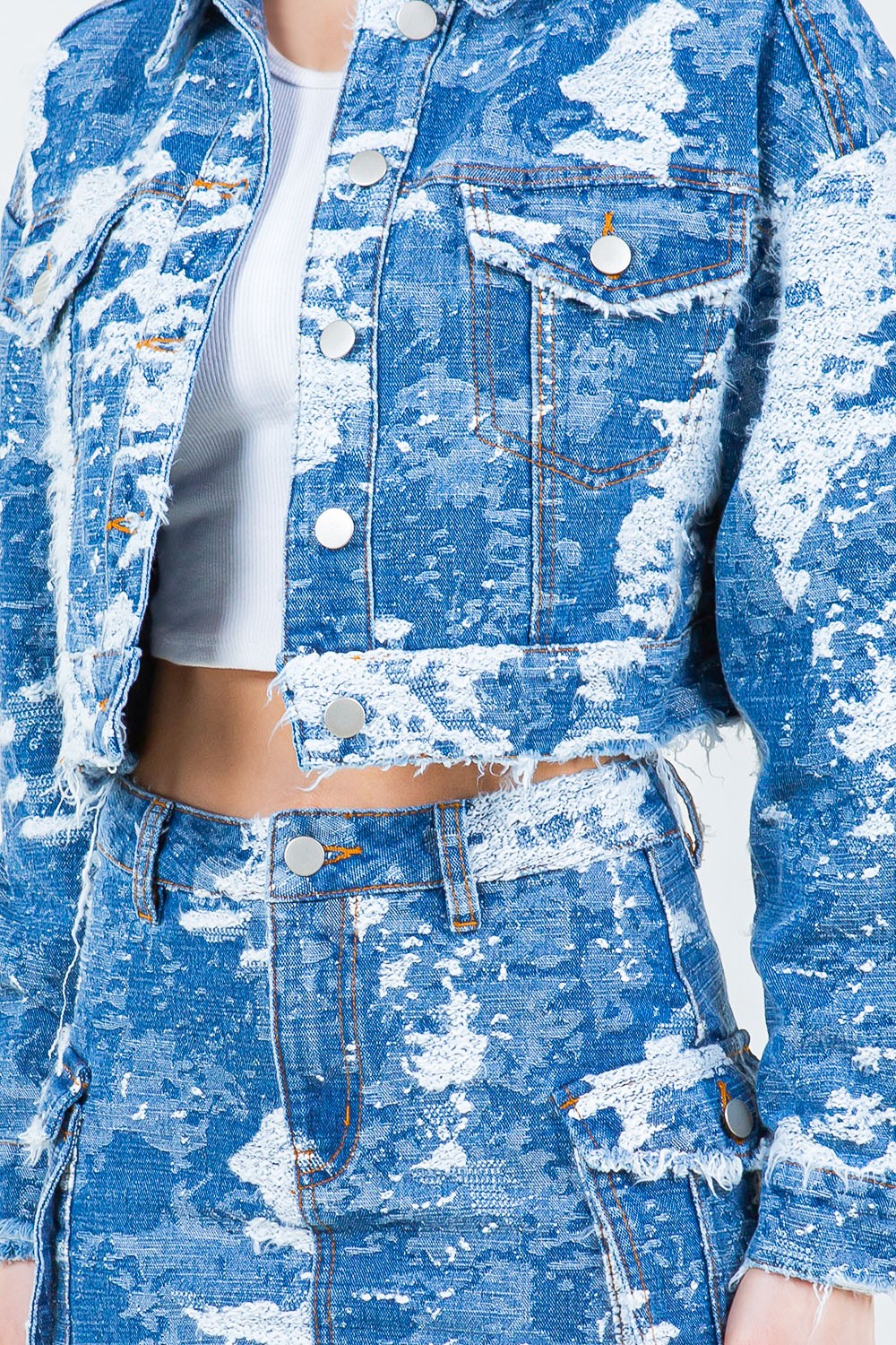 A person wearing the American Bazi Jacquard Trim Cropped Denim Jacket in blue and white distressed denim, paired with a matching skirt, stands against a plain background.