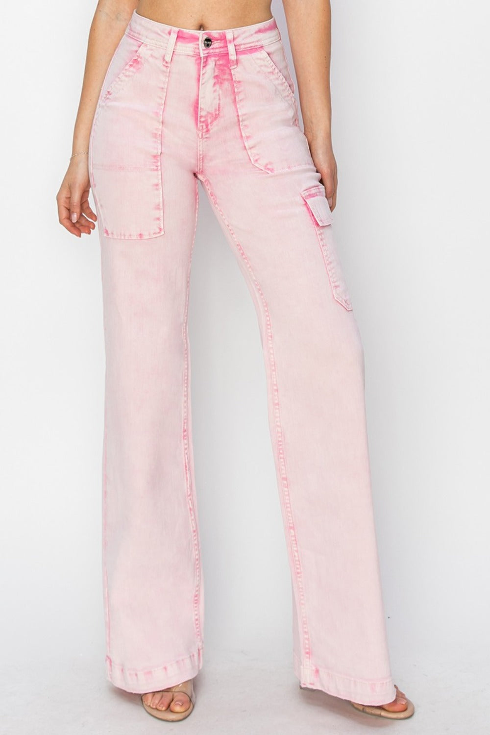 Person wearing the RISEN Full Size High Rise Wide Leg Cargo Pocket Jeans in light pink, featuring front pockets and a button-zip closure, standing against a white background.