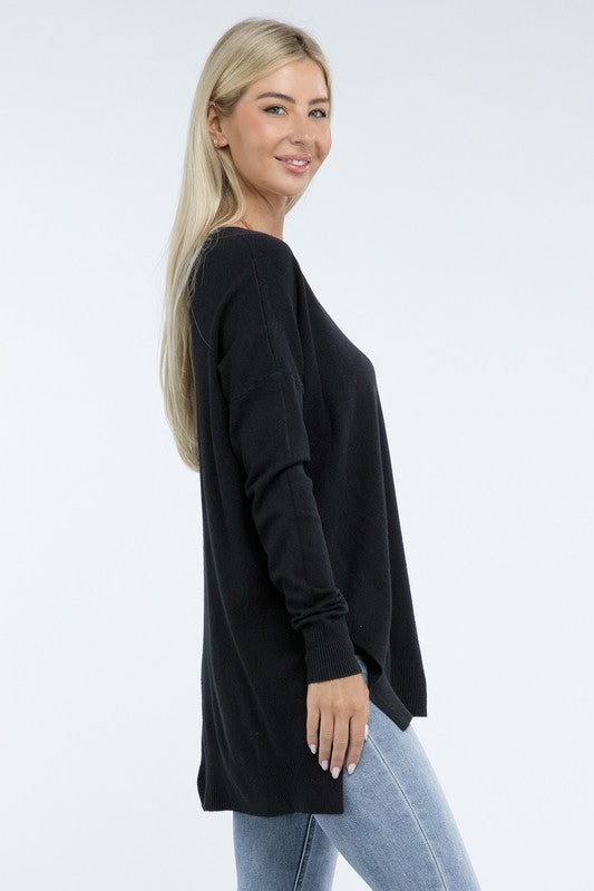 A person wearing a Hi-Low Hem Front Seam Sweater in brown and light blue jeans stands with hands partly in pockets. The individual has long hair and wears a necklace.