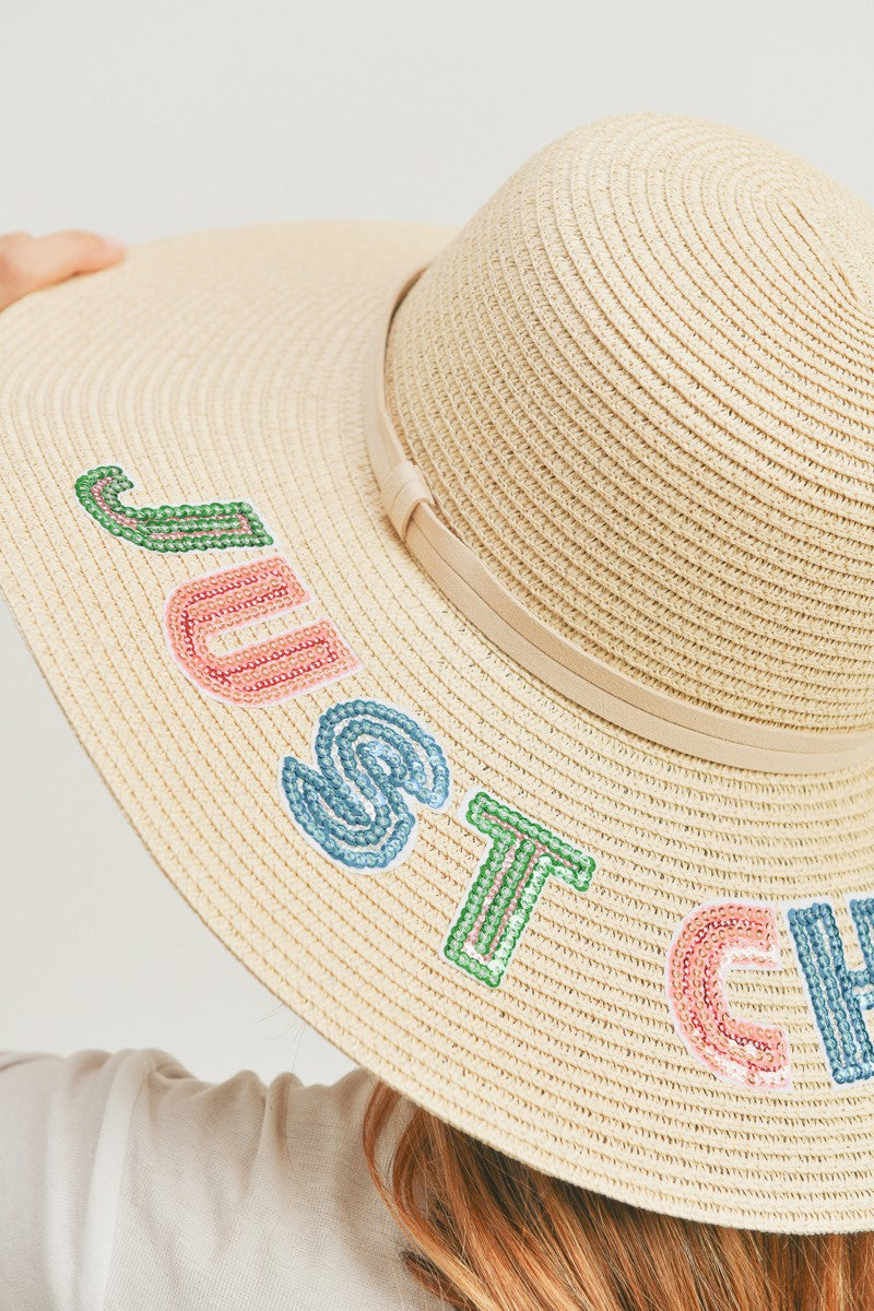 Wearing the Fame Sequin Letter Graphic Wide Brim Straw Hat, a person with long hair embraces a summer look, featuring the colorful sequin letters "JUST CHILL OUT.