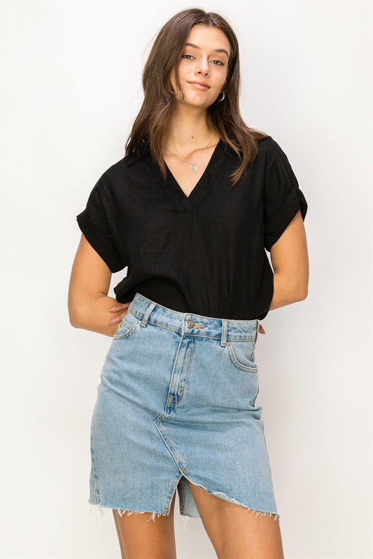 A woman with long hair is wearing the Always a Delight Short Sleeve Linen Top in brown and black pants, standing against a beige background.