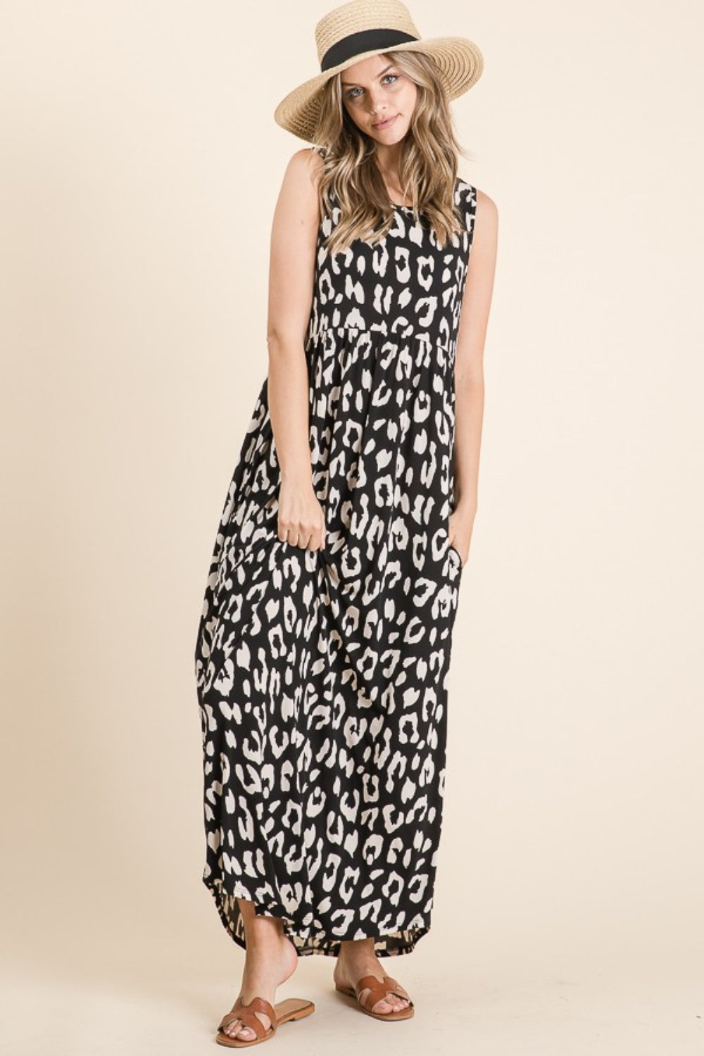 A person wearing the BOMBOM Leopard Maxi Dress with Pockets, paired with brown sandals, is standing against a beige background.