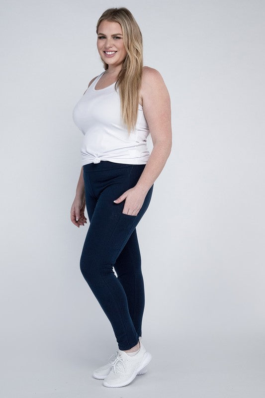 A person with long hair in casual attire is wearing a white t-shirt, Plus Everyday Leggings with Pockets in black, and white sneakers. They are holding a white cap and sporting a black crossbody bag.