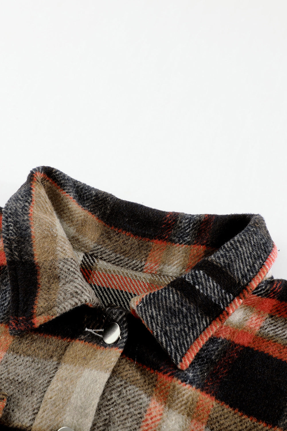 A person wearing a Brown Plaid Button Up Long Sleeve Flannel Shacket layered over a white top with ripped jeans and holding a brown handbag stands against a textured gray wall.