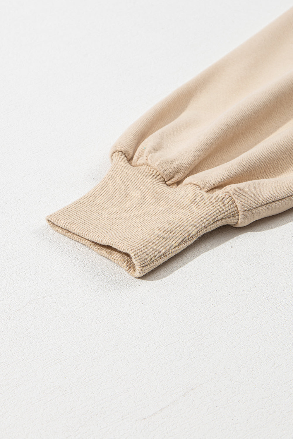 A person with long brown hair is standing with their back to the camera, wearing a Parchment Solid Kangaroo Pocket Half Zipper Oversized Hoodie and black shorts.