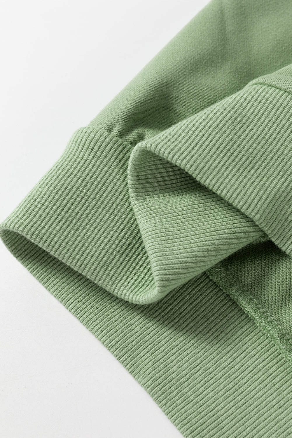 A person wearing a Grass Green Leopard Print Colorblock Raglan Sleeve Sweatshirt stands in front of a brick wall.