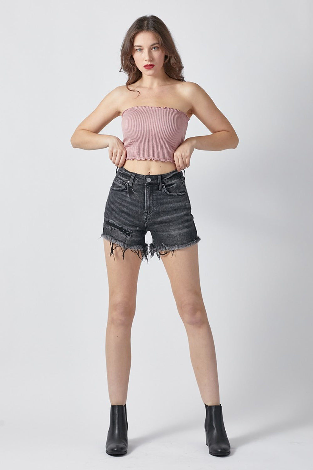 A person wearing RISEN Raw Hem Denim Shorts with Pockets, featuring high-waisted, distressed black design and a button and zipper closure, perfect for summer outfits.