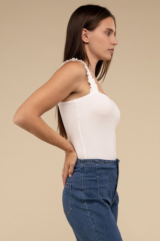 A young woman in a chic Ribbed Ruffle Strap Bodysuit and ripped denim shorts poses against a plain background.